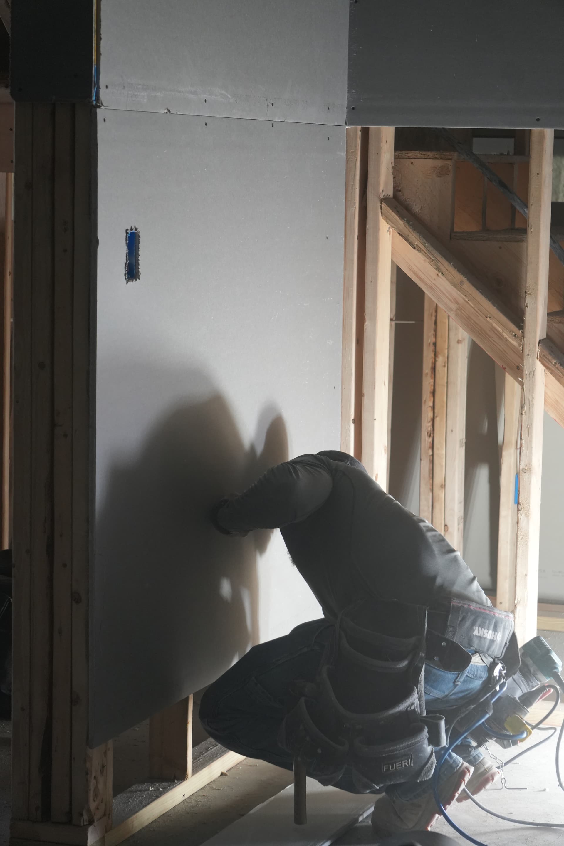 Worker installing blueboard onto wall framing