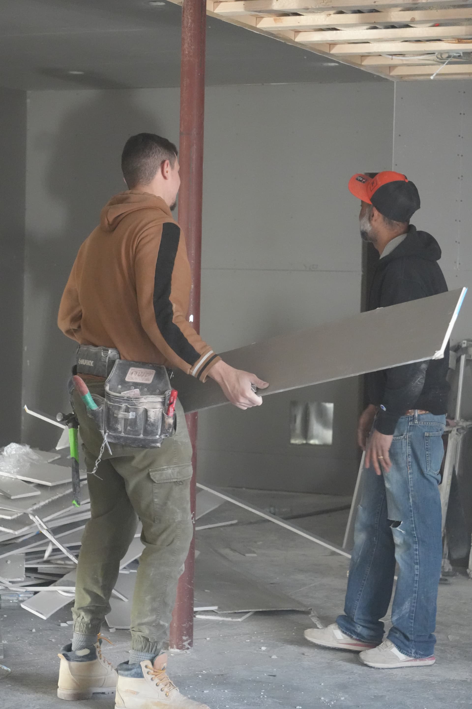 Two-man crew installing blueboard panel on scaffold