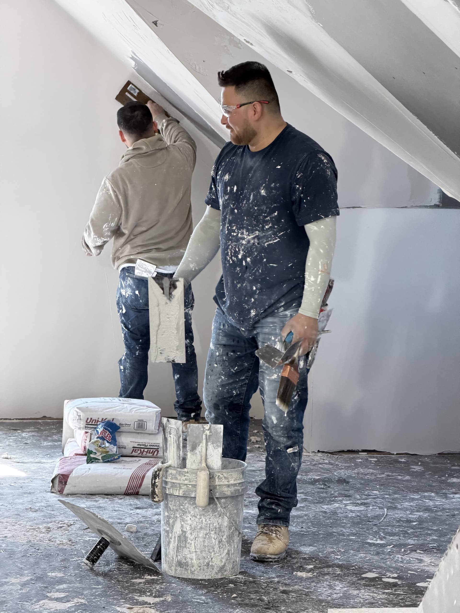 Two plasterers working together in vaulted ceiling space
